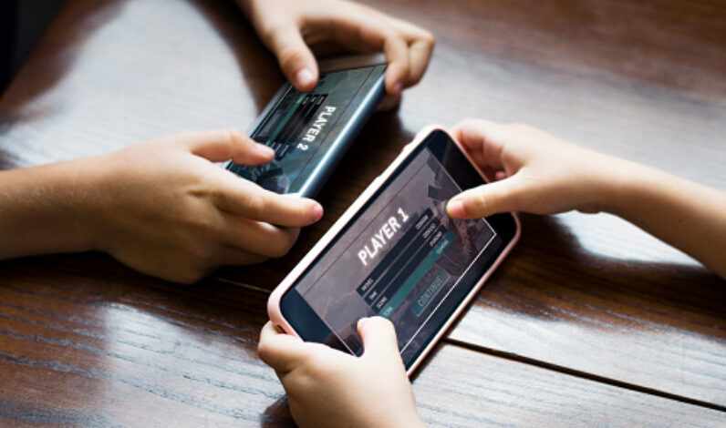 Little boy playing a mobile game against his sister